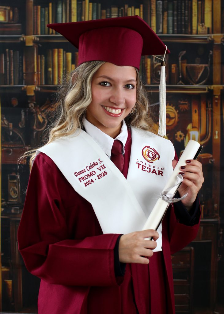 A smiling graduate in a maroon cap and gown holds a diploma wearing a stole labeled Colegio Tejar PROMO VII